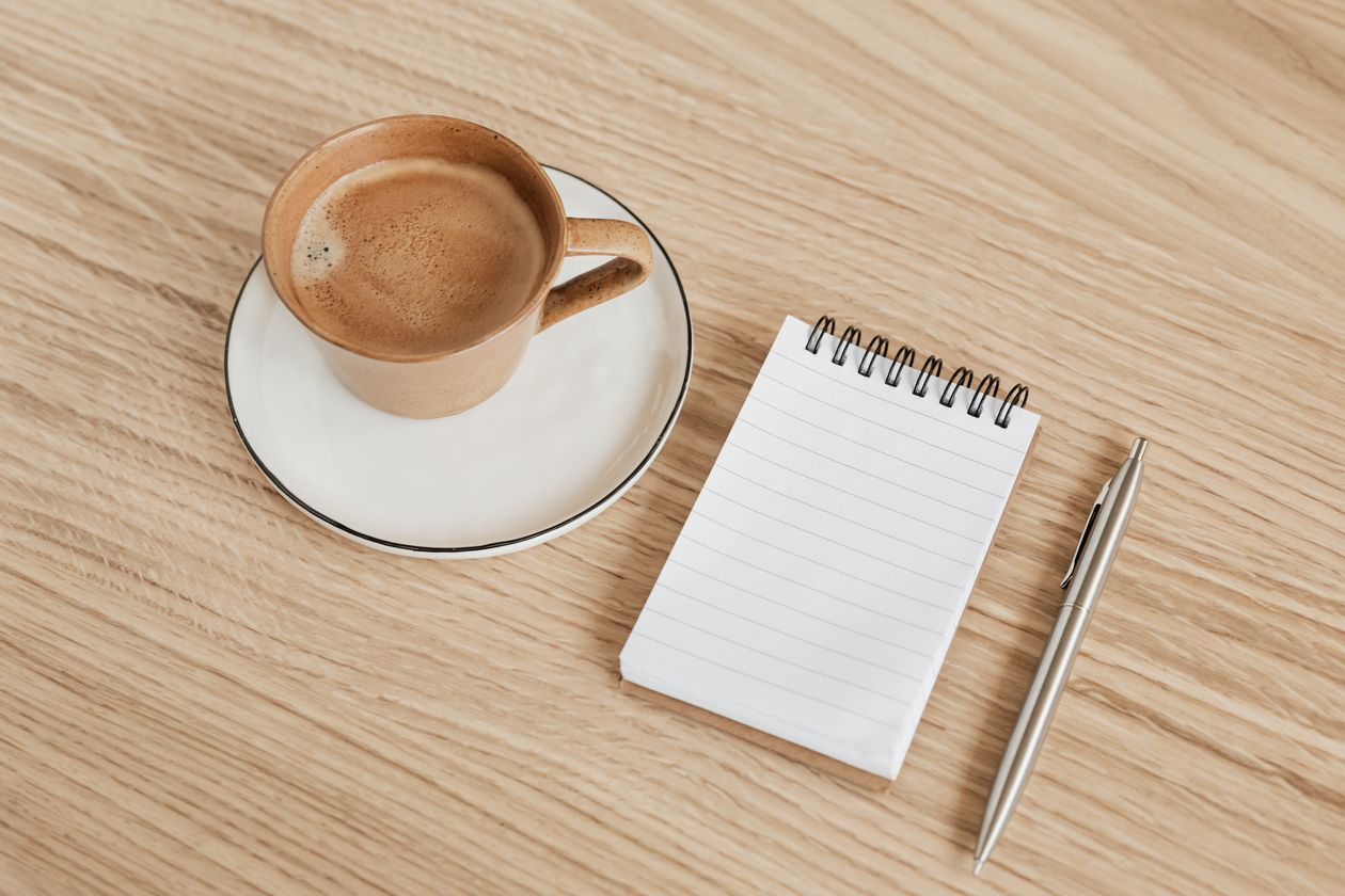 Open notebook with pen and coffee for plotting cozy mystery suspects