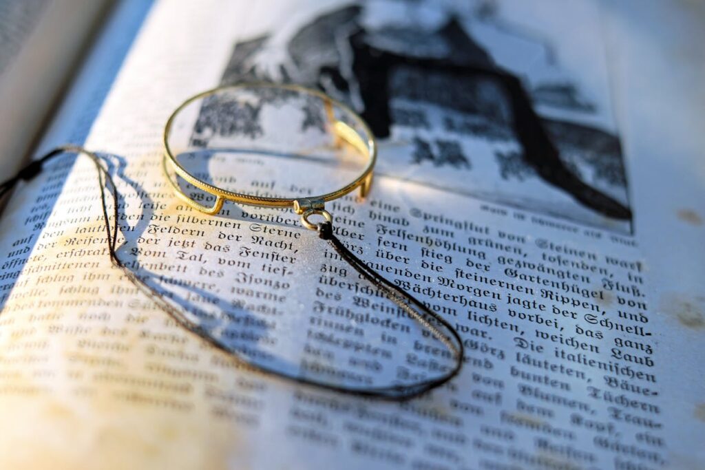 Magnifying glass on an open book illustrating red herrings in cozy mystery writing