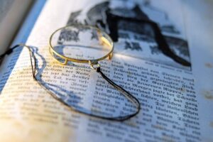 Magnifying glass on an open book illustrating red herrings in cozy mystery writing