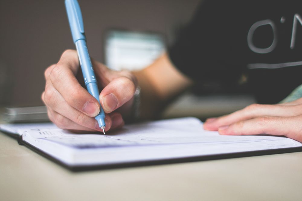 Hand writing in a notebook while revising telling into showing